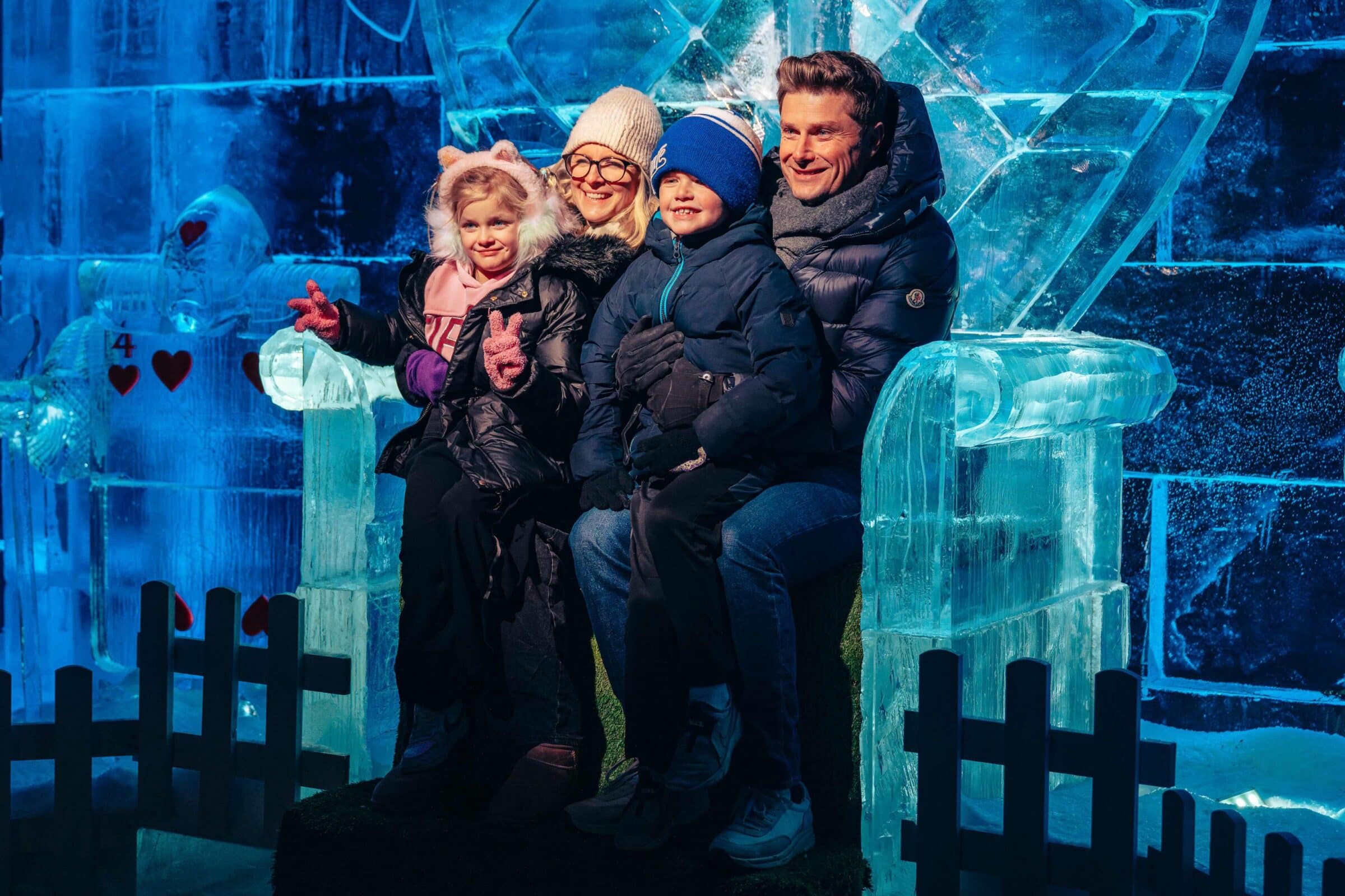 Young family poses on ice sculpture at the Magical Ice Kingdom at Winter Wonderland
