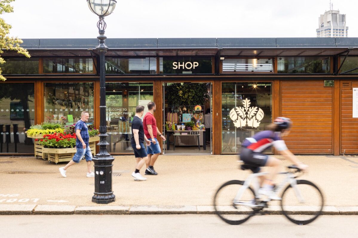 Glass-fronted shop entrance with a golden leaf design, open door showcasing elegant interior decor under a sunny blue sky.