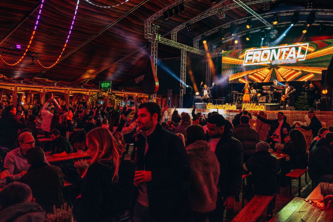 Groups of people enjoying drinks and food in the Bavarian Hall at Winter Wonderland whilst a band plays in the background