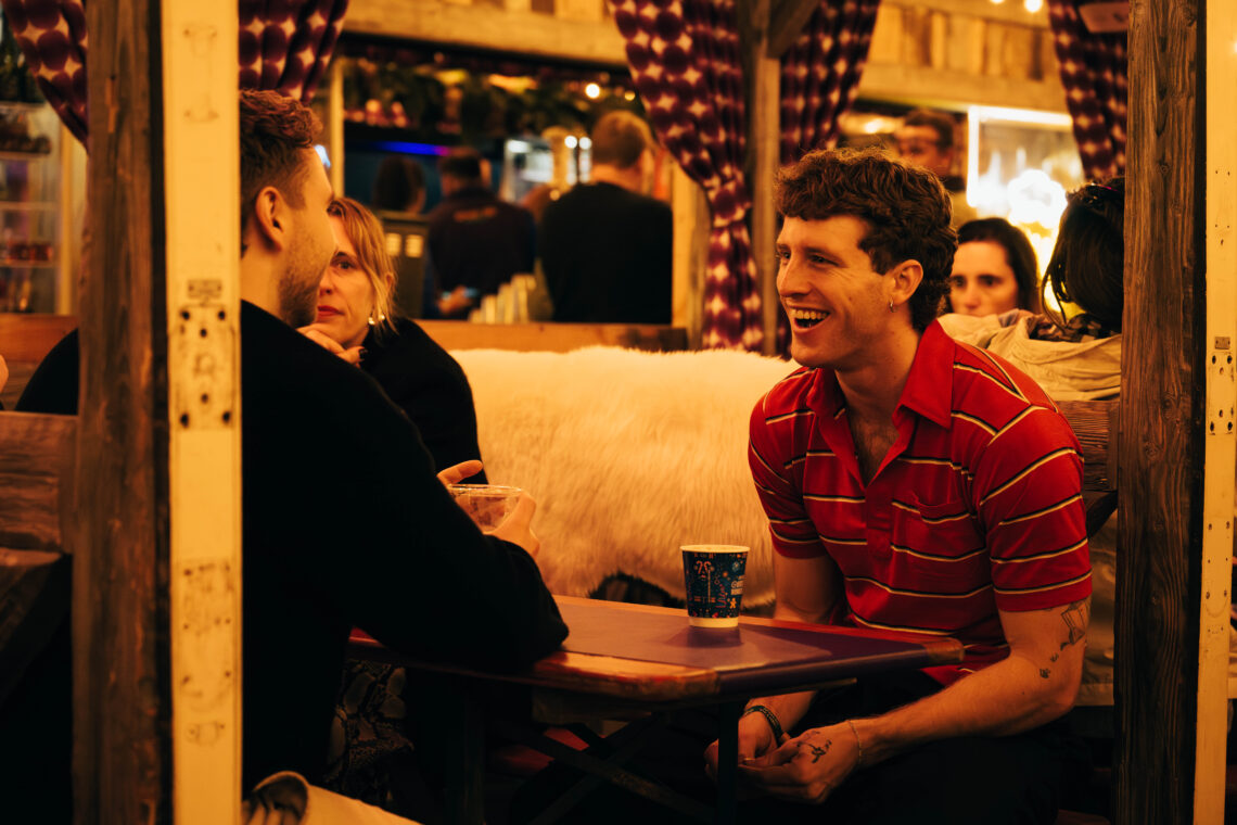 Group of young people enjoying festive drinks in a booth at Winter Wonderland