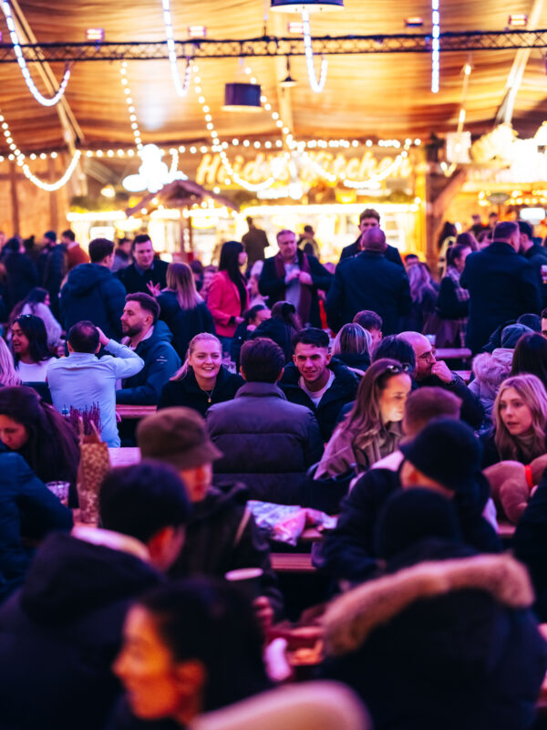 Group of people sitting at tables in the Bavarian Village at Hyde Park Winter Wonderland
