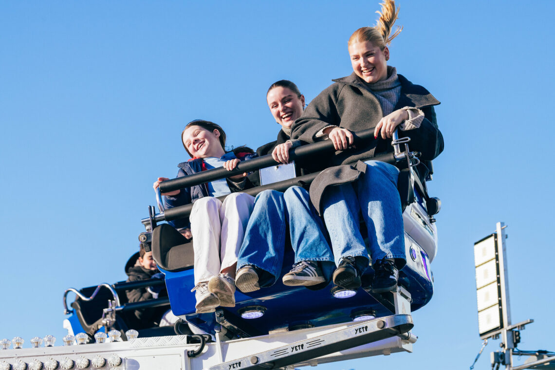 A group of three women enjoying a ride in the bright sunshine at Winter Wonderland