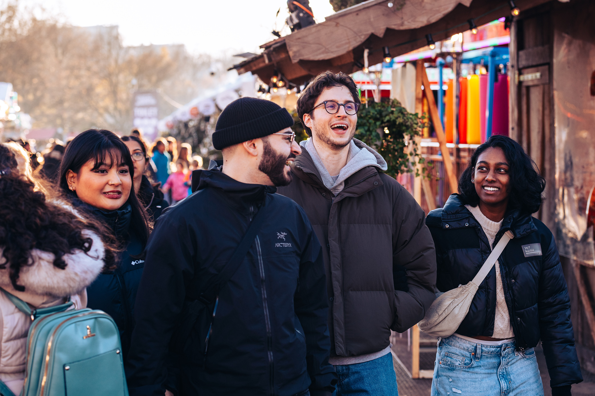Group of four young people walking through Winter Wonderland, laughing and smiling